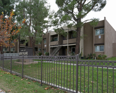 Wide-angle view of Rodeo Village, featuring the gated community entrance and multiple residential buildings, emphasizing the spacious outdoor environment and greenery.