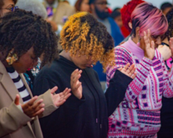 Congregation members at Lily of the Valley Christian Center in prayer, showing diverse attendees engaged in spiritual reflection.