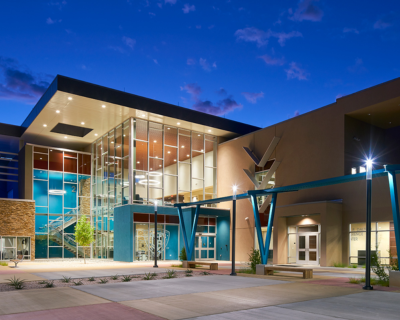 Modern utility facility at twilight with large glass windows, vibrant blue structural accents, and welcoming entrance, reflecting advanced architectural design and community focus